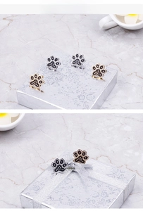 Macro shot of paw-shaped stud earrings with black and white rhinestones in a gift box