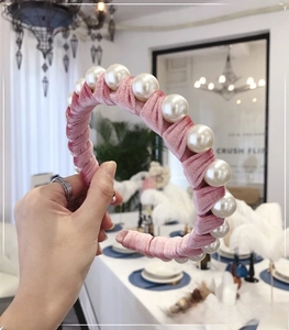 Close-up of pink velvet headband with large white pearls shown in a lifestyle setting