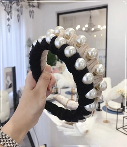 Detail of twisted velvet headband with large pearls and beige black woven texture