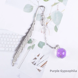 Detailed silver feather bookmark with purple dried flower glass ball pendant on a desk