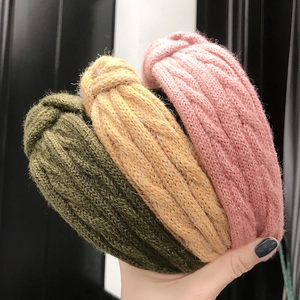 Close-up of three knitted twist headbands in olive green, mustard yellow, and pink colors
