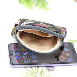 Floral print fabric coin purse in black and pink shown next to a smartphone for size scale
