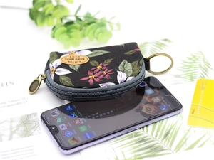 Floral semicircular coin purse with key ring on a smartphone for size reference