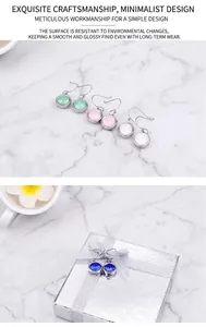 Detail of round colorful zircon drop earrings with a stylish blue pair and silver gift box