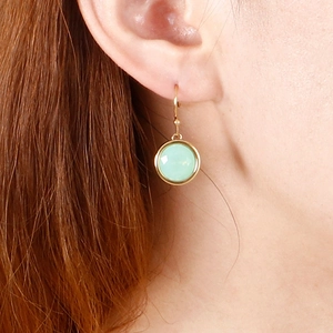 Elegant gold earrings with round green zircon stones shown on a model's ear
