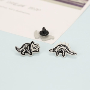 Front and back detail of black and white cartoon dinosaur skeleton enamel pins with rubber back