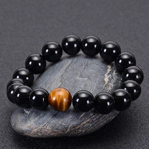 Detailed close-up of natural black agate and tiger eye stone beads on textured stone base