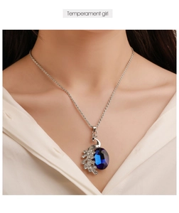 Primo piano della collana con ciondolo a pavone e cristallo blu scuro su modella