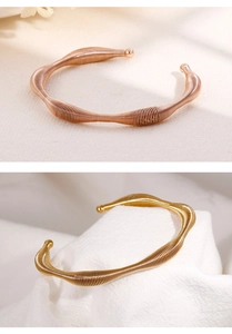 Detailed macro view of spiral textured open bangle in gold and rose gold titanium steel