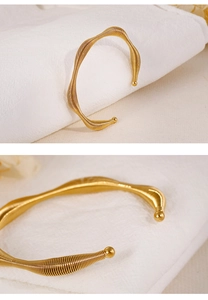 Macro detail of wave-shaped golden stainless steel bracelet with textured coil pattern