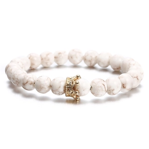 White marble bead bracelet with a gold crown charm centerpiece on white background
