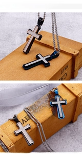 Detail of cross pendant necklace with tiered metal design on a vintage wooden box