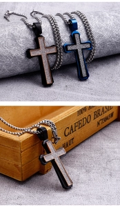 Detail of matte black and blue cross pendants with silver box chains on a wooden box