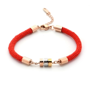 Close-up of red braided rope bracelet with tricolor gold cylinder rings and screw design