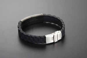 Gros plan d'un bracelet en silicone noir avec sangle texturée et plaque métallique argentée