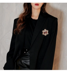 Vintage starburst brooch with red gemstone pinned on a black tailored blazer lapel