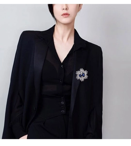 Detailed view of a vintage silver flower brooch with blue crystals on a black suit blazer
