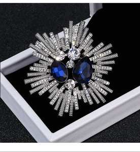 Macro shot of silver sunflower brooch with blue drop stones and clear zircon crystals