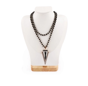 Detail of a black beaded necklace with large geometric triangle pendant on wood base