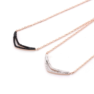 Detail view of double-layered rose gold V-shaped pendants with black and white crystals