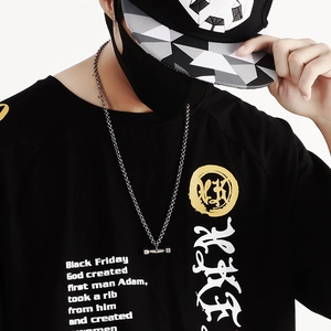 Collier avec pendentif haltère en argent porté avec un t-shirt noir au style urbain