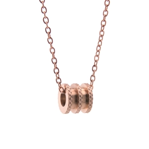 Gros plan du pendentif cylindrique texturé en or rose sur collier minimaliste en titane