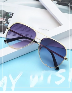 Detail of aviator sunglasses with gold metal frame and purple-blue gradient lenses