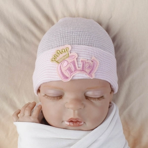 Detailed shot of pink and white striped baby hat with embroidered gold crown Girl patch