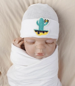 Detail of soft white baby knit hat featuring cactus and sunflower embroidery patch