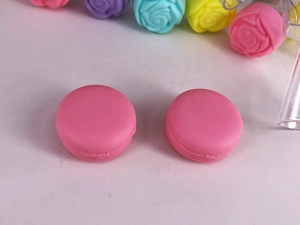 Top view of pink macaron cosmetic containers on a decorative rose flower background