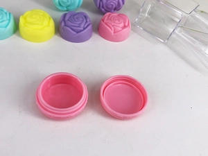 Close-up of pink macaron plastic jar with embossed rose lid and open view for cream storage