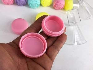 Detailed view of an open pink macaron-shaped plastic cream jar held in hand
