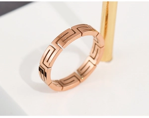Detail shot of a rose gold titanium steel ring with an intricate Greek key cutout pattern