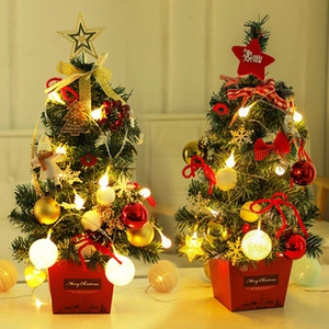 Close-up of small tabletop Christmas trees with LED lights and festive ornaments