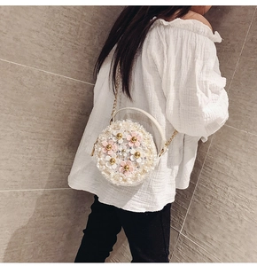 White round shoulder bag with pink flowers and pearls on a model back for size reference