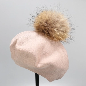 Close-up of pink wool knitted beret featuring a large fluffy brown fur pompom detail
