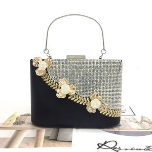 Close-up of evening clutch bag featuring golden metal rose relief and silver rhinestone details