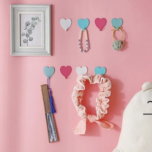 Pink, blue and white heart-shaped wall hooks set with accessories on pink wall