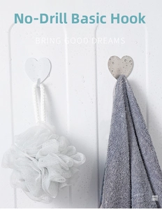 Detail of heart-shaped wall hooks holding a bath sponge and towel on a wet tiled surface