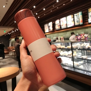 Handheld view of a 150ml coral pink mini vacuum flask with a natural wood grain lid