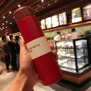 Close-up of a 150ml matte red mini insulated flask with a wood grain lid held in hand