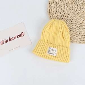 Close-up of a bright yellow ribbed knit beanie featuring a minimalist white woven label