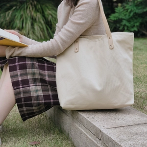 Large off-white canvas tote bag with brown PU leather handles and reinforced rivets