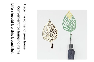 Creative gold and green leaf-shaped wall hook showing a folded umbrella hanging in a home corner