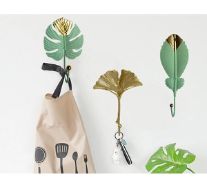 Detail showing Nordic gold and green metal leaf wall hooks holding keys and apron