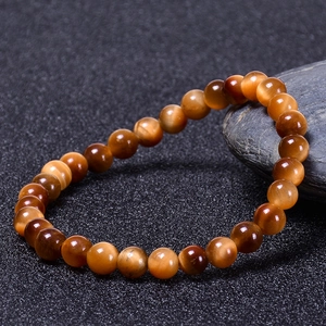 Macro shot of natural sun tiger eye stone bracelet with cat eye effect on dark stone
