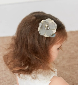 Close-up of a child hair clip featuring fabric flowers with pearls and rhinestones
