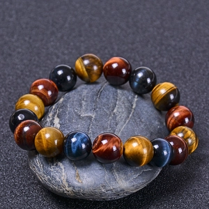 Macro shot of polished yellow and red tiger eye beads on a zen river stone