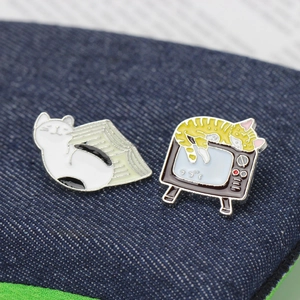 Pins mignons en émail avec chat près de livres et chat dormant sur une télé rétro