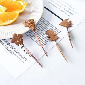 Close-up of four bronze-finish vintage fruit forks with bear and floral handle designs